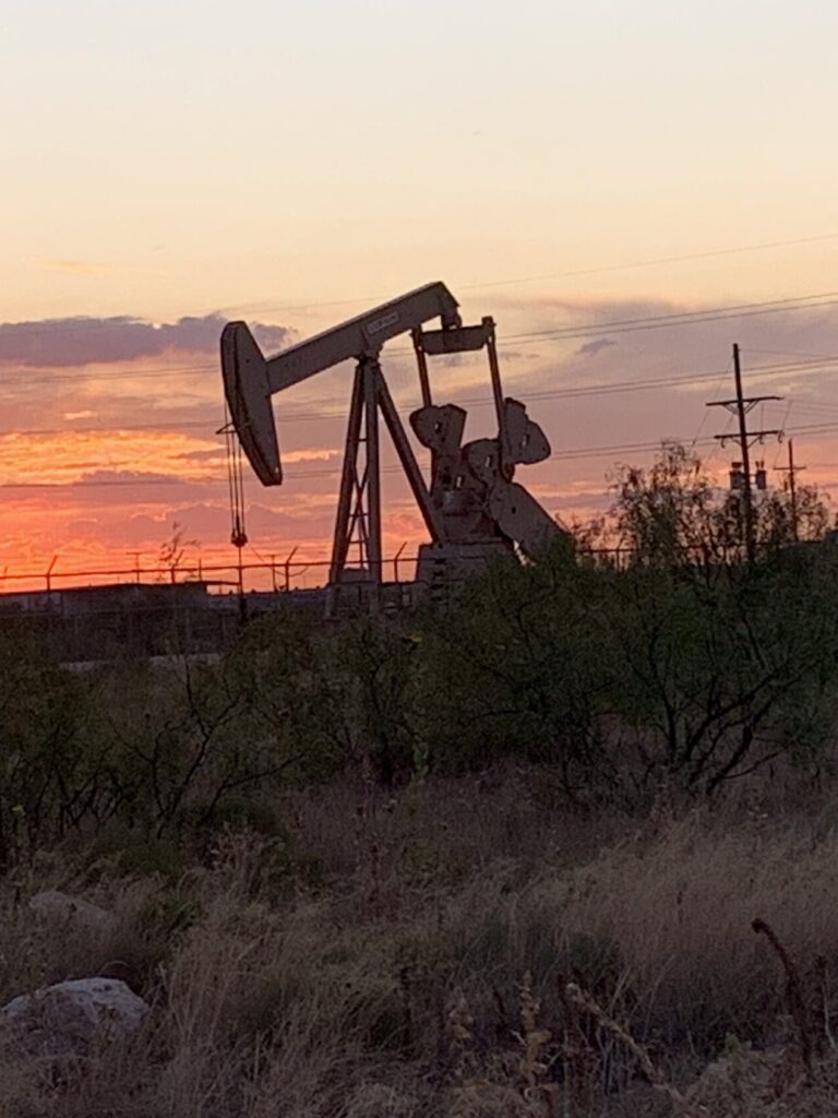 Oil pumpjack silhouetted against an orange sunset in the Permian Basin near Midland, TX
